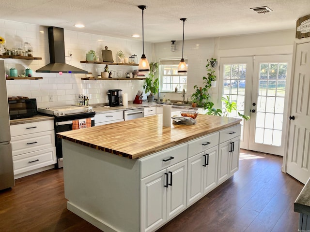 kitchen with a kitchen island, island range hood, butcher block counters, stainless steel appliances, and white cabinets