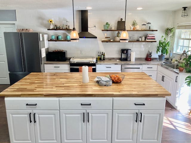 kitchen featuring range hood, stainless steel appliances, wood counters, and white cabinets