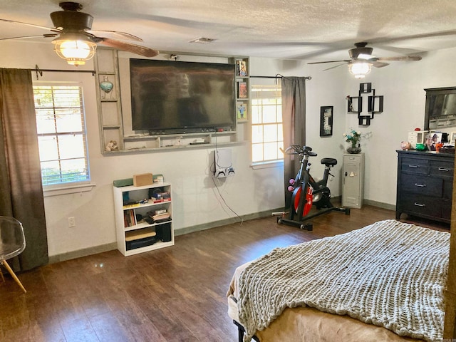 bedroom featuring ceiling fan, a textured ceiling, and dark hardwood / wood-style floors