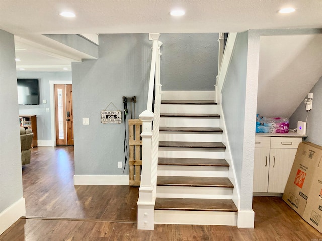 stairs featuring a textured ceiling and hardwood / wood-style flooring