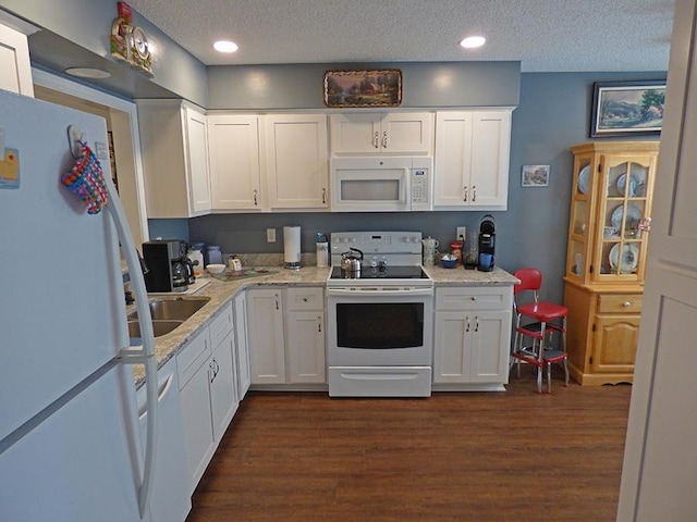 kitchen with white cabinets, light stone counters, a textured ceiling, white appliances, and dark hardwood / wood-style flooring