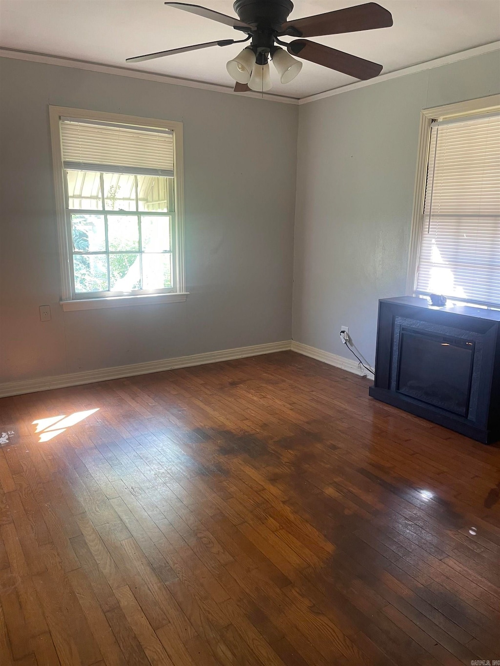 empty room with ornamental molding, ceiling fan, and dark hardwood / wood-style flooring