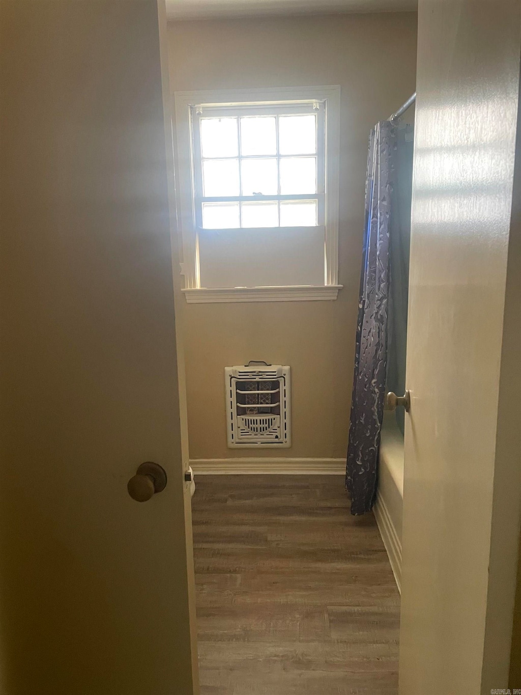 bathroom featuring shower / bath combo, wood-type flooring, and heating unit