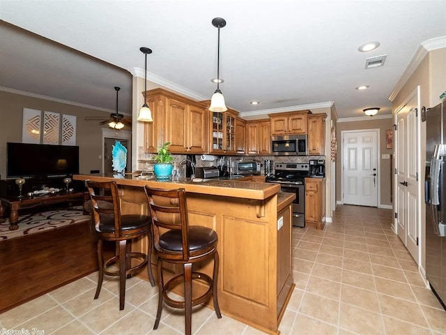 kitchen featuring kitchen peninsula, decorative backsplash, a breakfast bar, stainless steel appliances, and crown molding