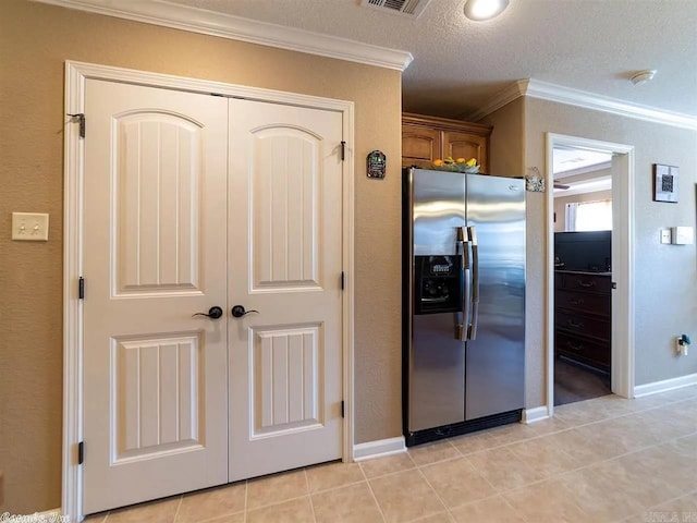 kitchen featuring stainless steel refrigerator with ice dispenser, a textured ceiling, light tile patterned floors, and ornamental molding