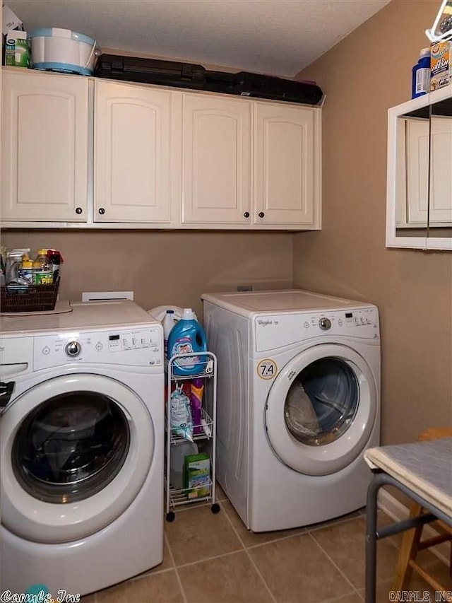 laundry area featuring washer and dryer, light tile patterned floors, and cabinets