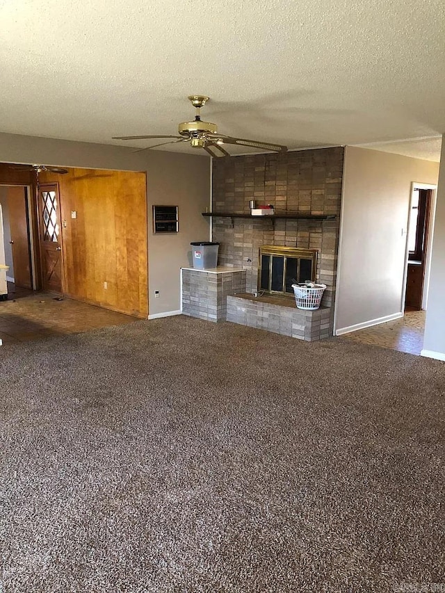 unfurnished living room with a textured ceiling, ceiling fan, carpet flooring, and a brick fireplace