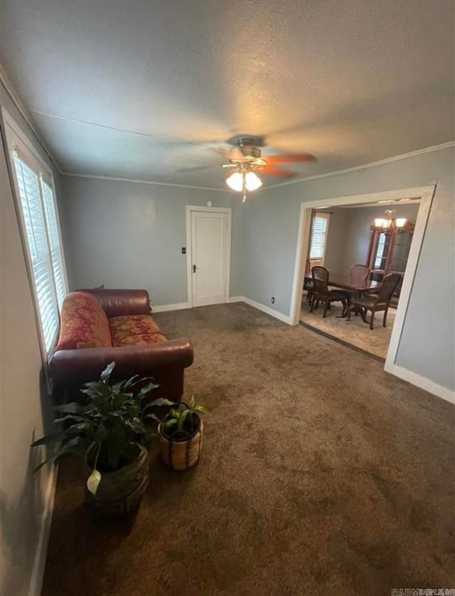 carpeted living room featuring ornamental molding, a healthy amount of sunlight, and ceiling fan with notable chandelier