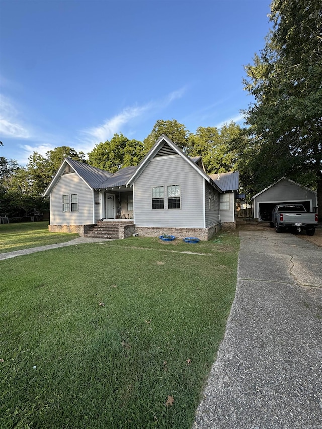 view of front of house featuring a front lawn, an outbuilding, and metal roof