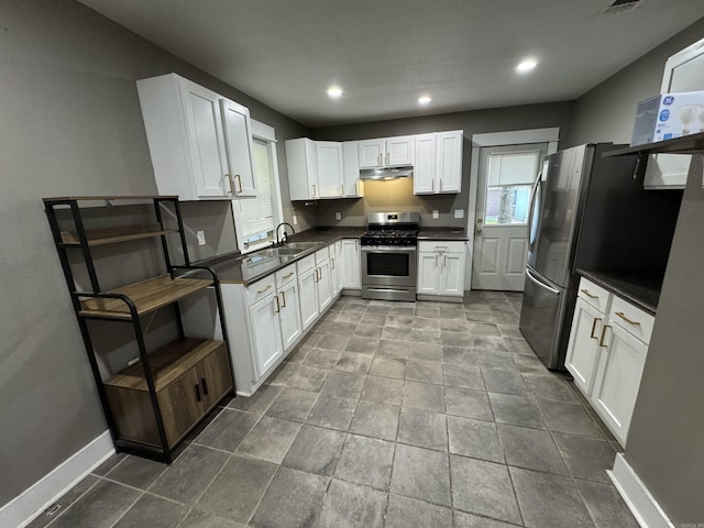 kitchen with dark countertops, appliances with stainless steel finishes, under cabinet range hood, and a sink