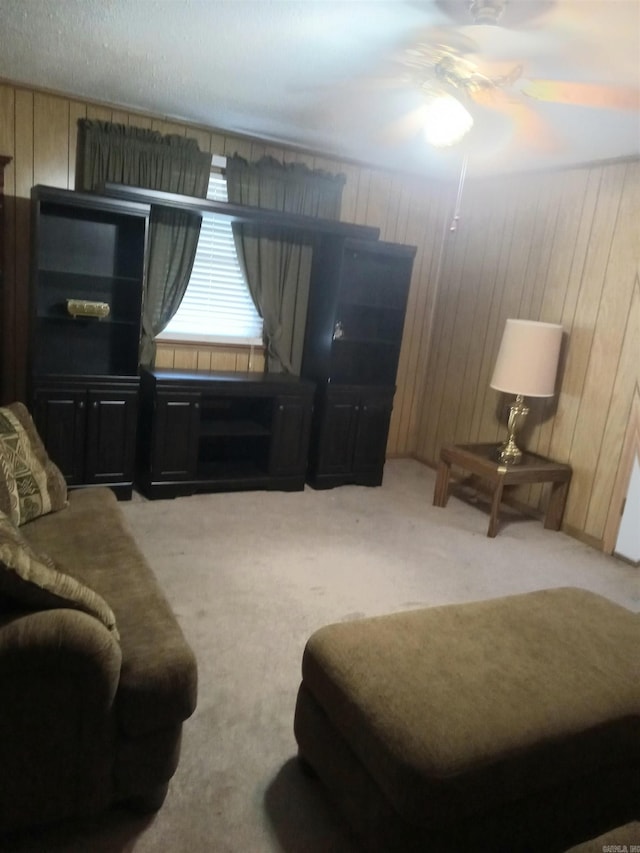 carpeted living room featuring wooden walls and ceiling fan