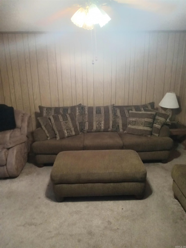 carpeted living room featuring ceiling fan and wood walls