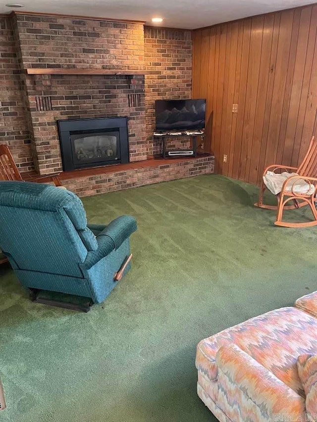 carpeted living room with a brick fireplace and wooden walls