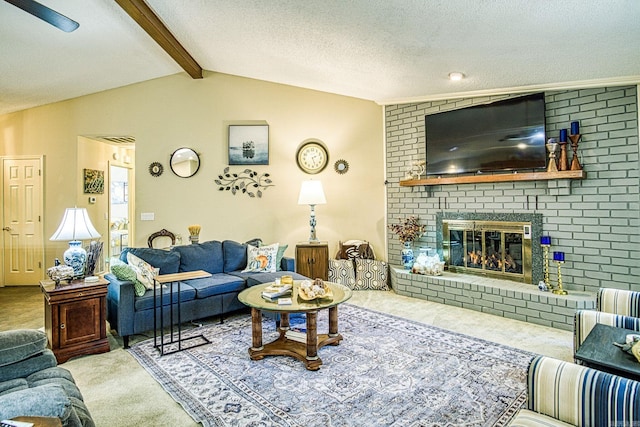 carpeted living room with ceiling fan, a textured ceiling, a brick fireplace, and vaulted ceiling with beams