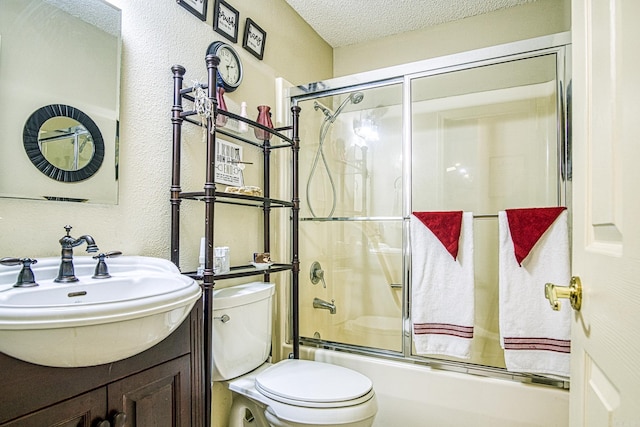 full bathroom with vanity, combined bath / shower with glass door, a textured ceiling, and toilet