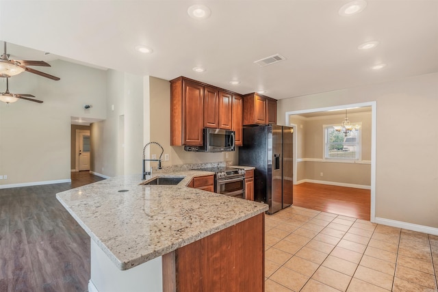 kitchen with light stone counters, sink, kitchen peninsula, and stainless steel appliances