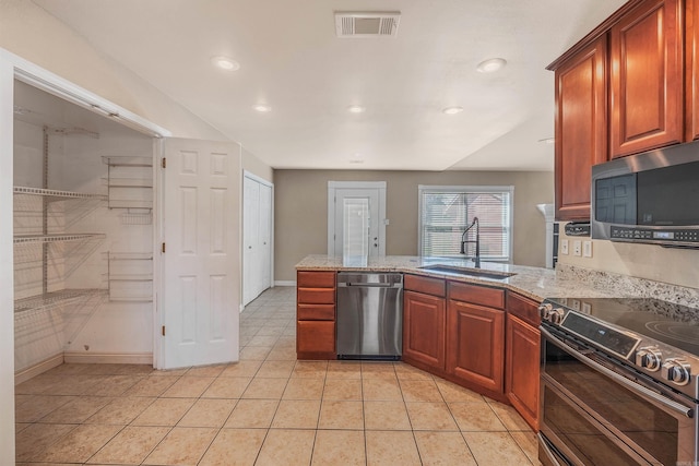 kitchen with kitchen peninsula, light stone counters, light tile patterned flooring, sink, and stainless steel appliances