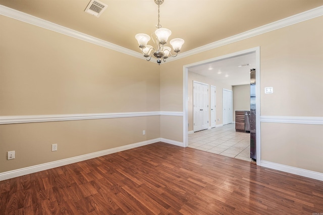 empty room with ornamental molding, light hardwood / wood-style flooring, and an inviting chandelier