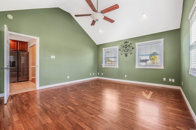 unfurnished room featuring ceiling fan, high vaulted ceiling, and light wood-type flooring