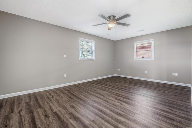 spare room featuring dark wood-type flooring, ceiling fan, and a wealth of natural light