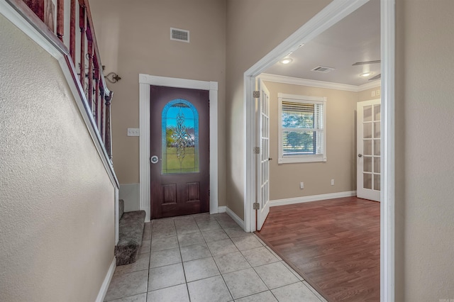 foyer entrance with light hardwood / wood-style floors and ornamental molding