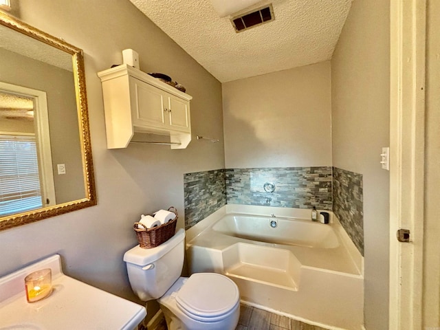 bathroom featuring toilet, a tub to relax in, a textured ceiling, and hardwood / wood-style floors