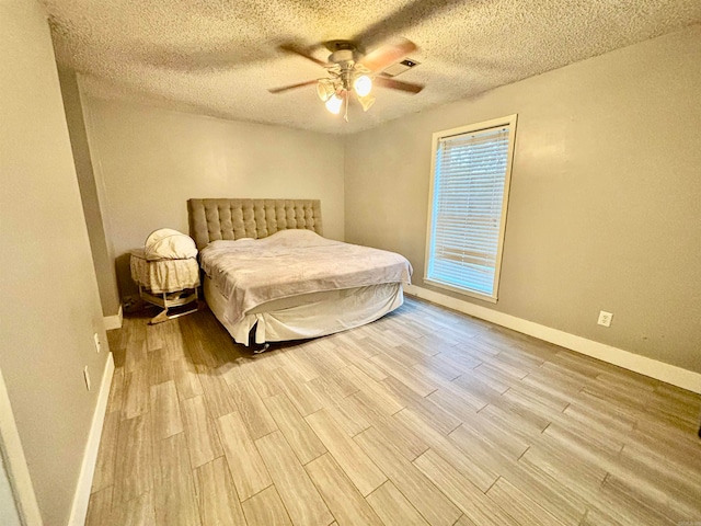 bedroom with a textured ceiling, light hardwood / wood-style floors, and ceiling fan