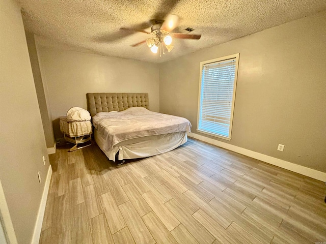 bedroom with a textured ceiling, light wood-type flooring, and ceiling fan