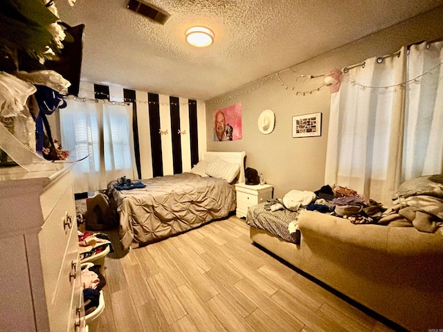 bedroom with a textured ceiling and light wood-type flooring