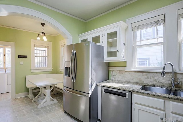 kitchen featuring sink, crown molding, stainless steel appliances, washer and dryer, and white cabinets