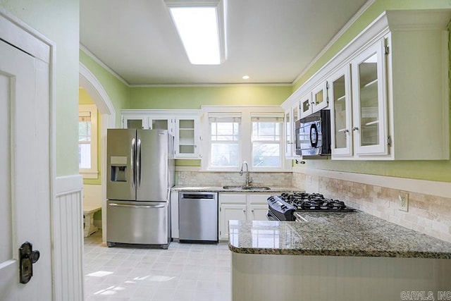 kitchen with sink, stainless steel appliances, ornamental molding, white cabinets, and stone countertops