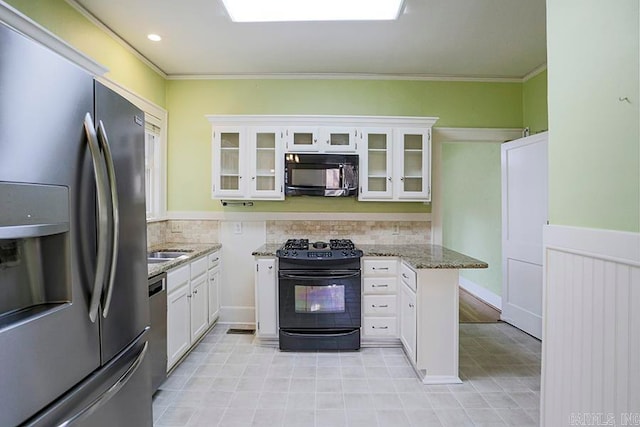 kitchen with light stone counters, white cabinets, ornamental molding, and black appliances