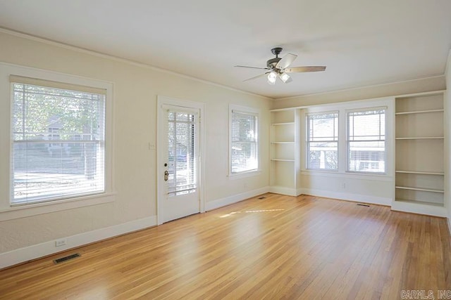 spare room with ornamental molding, ceiling fan, plenty of natural light, and light wood-type flooring