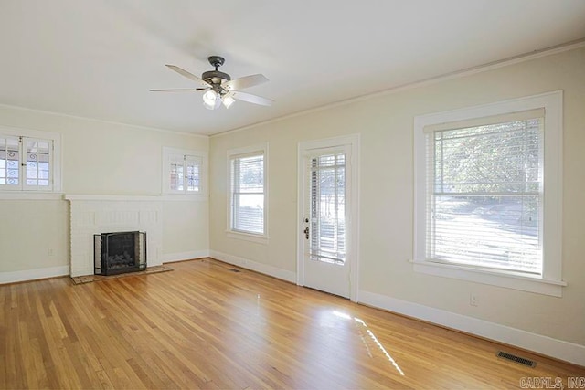 unfurnished living room featuring a wealth of natural light, a fireplace, and light hardwood / wood-style flooring