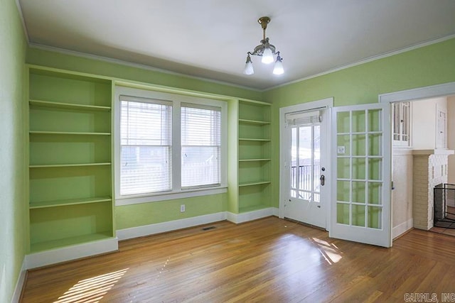 doorway featuring hardwood / wood-style flooring, crown molding, a brick fireplace, and built in features