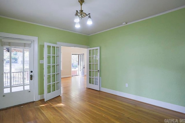 unfurnished room with french doors, wood-type flooring, crown molding, and a chandelier