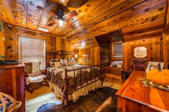 bedroom featuring wood ceiling, ceiling fan, light wood-type flooring, vaulted ceiling, and wooden walls