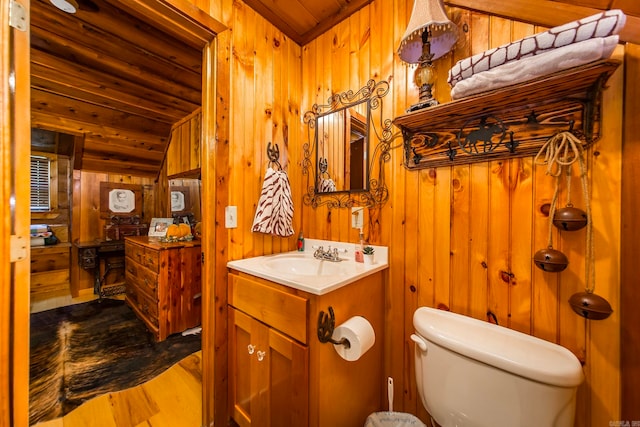 bathroom with wood walls, toilet, wooden ceiling, lofted ceiling, and vanity