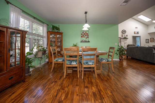 dining area with vaulted ceiling with skylight and dark hardwood / wood-style flooring