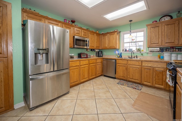 kitchen with light tile patterned floors, appliances with stainless steel finishes, sink, and hanging light fixtures