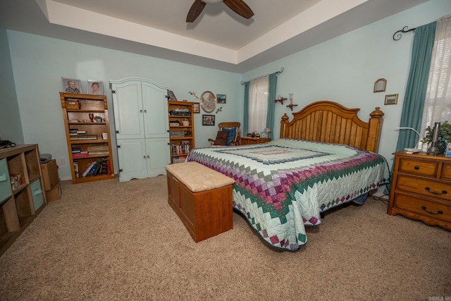 bedroom with ceiling fan, a raised ceiling, and light colored carpet