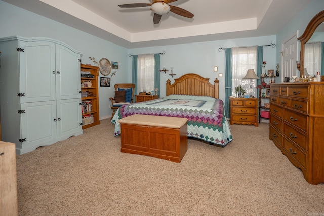 bedroom featuring light carpet, a raised ceiling, and ceiling fan