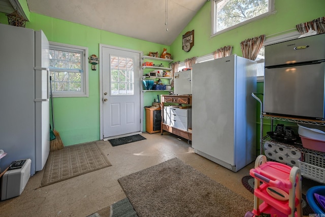 kitchen with concrete floors, vaulted ceiling, and white refrigerator