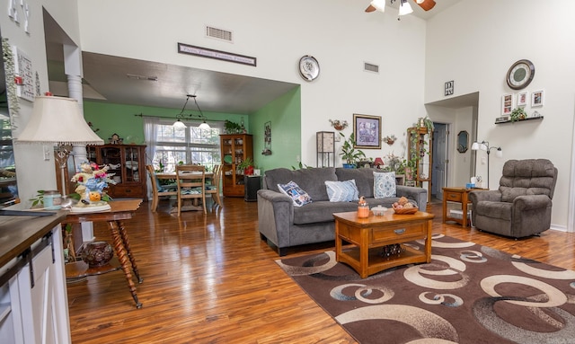 living room featuring ceiling fan, a towering ceiling, and hardwood / wood-style floors