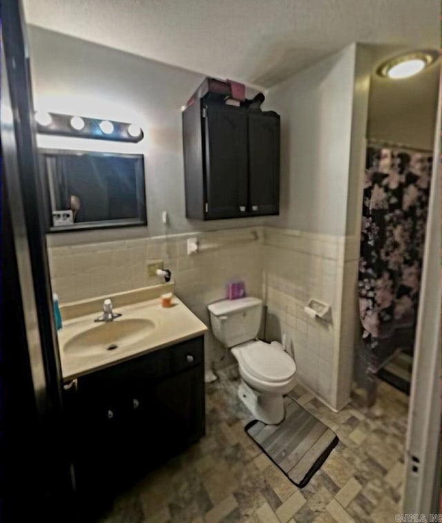 bathroom featuring tile walls, vanity, and toilet