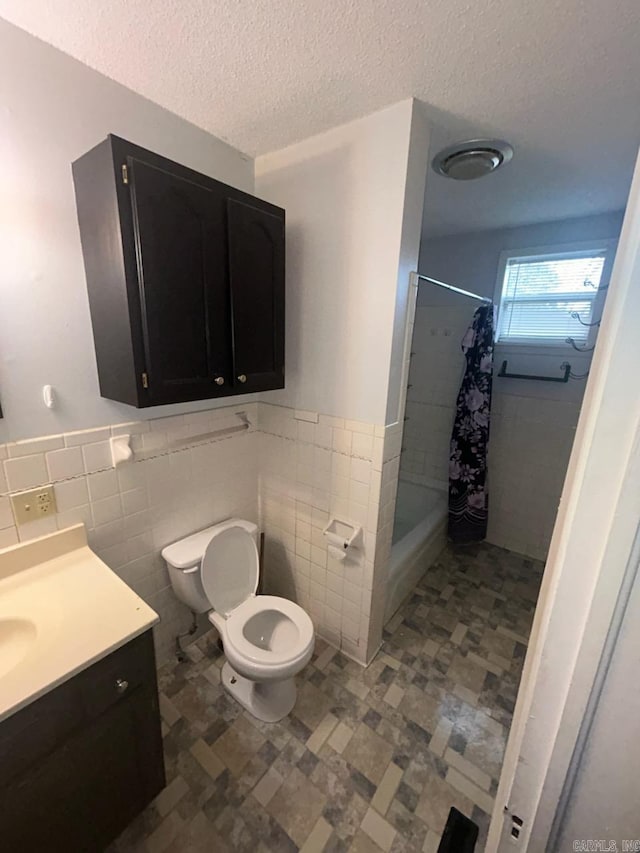 bathroom featuring tile walls, vanity, a textured ceiling, and toilet