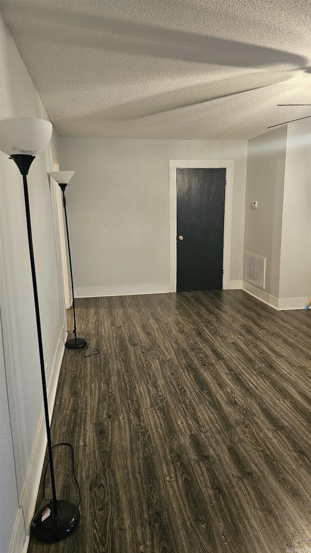 unfurnished room with dark hardwood / wood-style floors and a textured ceiling