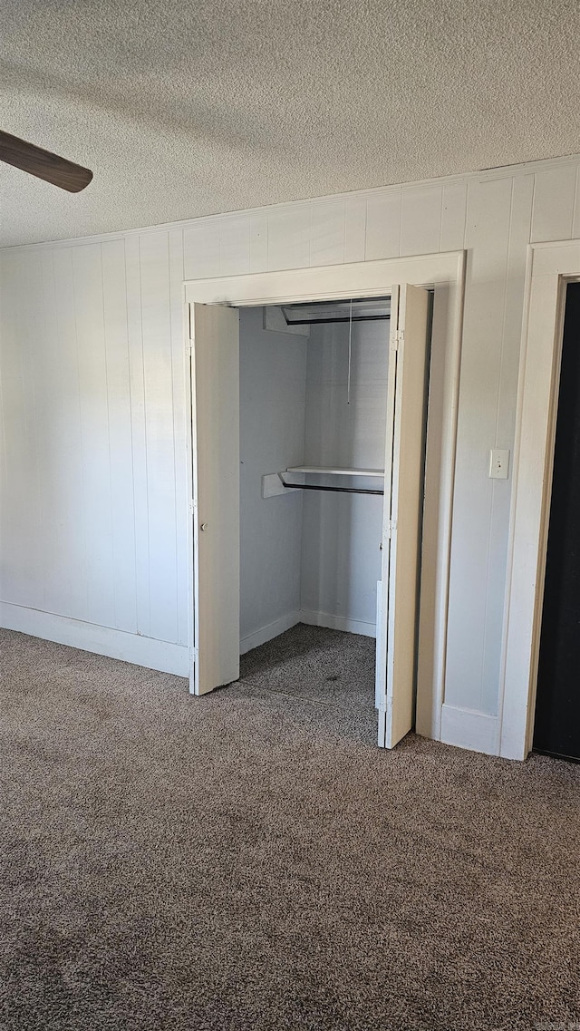 unfurnished bedroom with ceiling fan, carpet flooring, a closet, and a textured ceiling