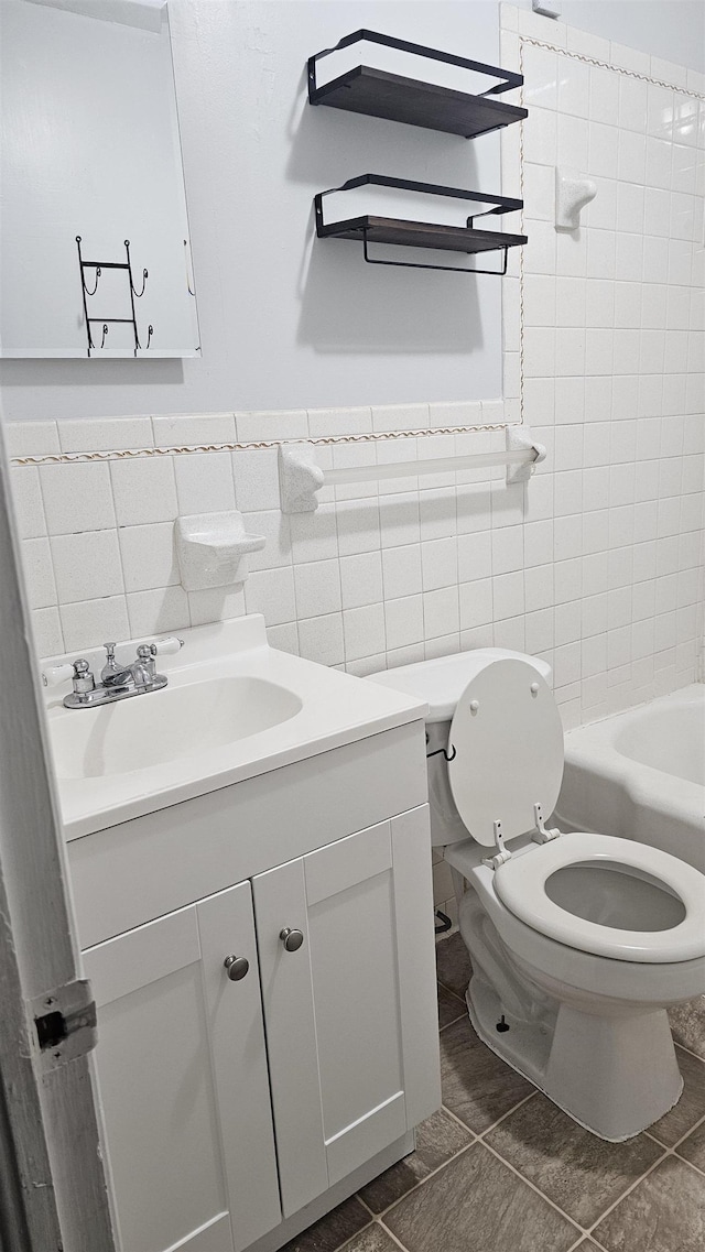 bathroom featuring vanity, toilet, tile patterned flooring, and tile walls