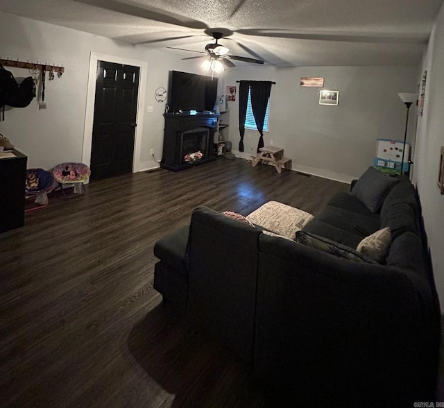 living room featuring ceiling fan, dark hardwood / wood-style floors, and a textured ceiling